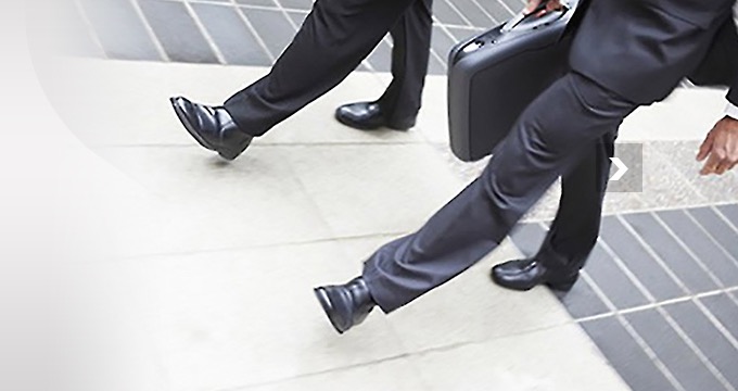 Two consultants walking briskly through a corporate atrium, briefcase in hand