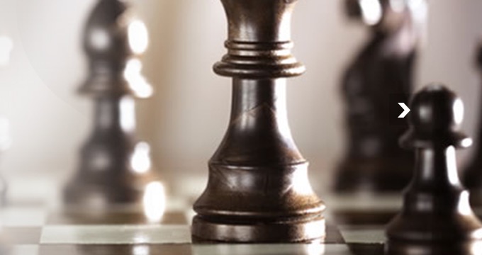 Chess pieces mid-match, the queen advanced ahead of the rest of the board